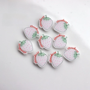 Close-up of pink resin strawberry charms with strawberry text for DIY phone cases