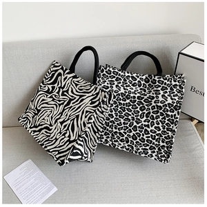 Detail of leopard and zebra print canvas tote bags on a sofa showing fabric texture