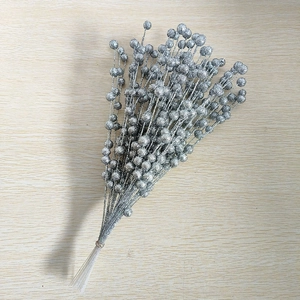 Silver glitter berry stems for Christmas decoration on a light wooden background