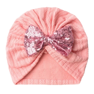 Pink knitted baby turban hat with a large sequined bow decoration for infants