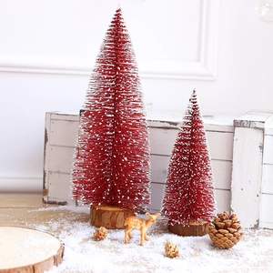 Mini red sisal Christmas trees with artificial snow and wooden bases on white wood background