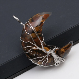 Detail of handmade silver wire tree of life wrapped around moon-shaped tiger eye stone
