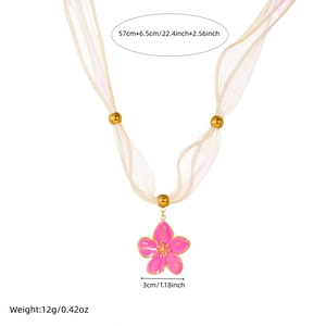 Detailed view of pink floral pendant necklace with beige ribbon and golden beads