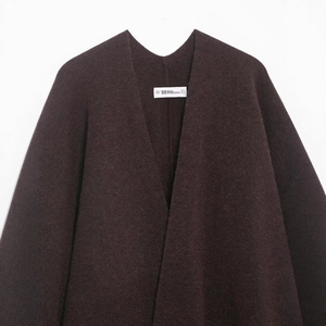 Women's burgundy knitted poncho coat with fringe details and textured fabric finish