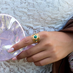 Close-up of bohemian gold ring featuring a green malachite stone on a model's finger
