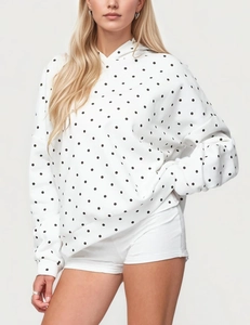 Close-up of women's white hooded sweatshirt featuring an all-over black polka dot pattern