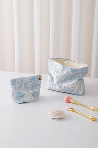 Detail of blue floral jacquard makeup bags with golden flower zipper and brand label