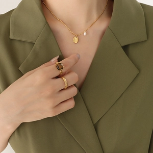 Titanium steel necklace with oval pendant and freshwater pearl on green blazer