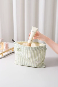 Dettaglio di una trousse da trucco in tela a righe con chiusura a coulisse e etichetta