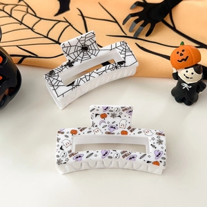 Detail view of Halloween hair claws featuring spooky spider webs and festive pumpkin patterns