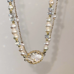 Detail of double-layer necklace with faux pearls, crystal beads and golden pendant