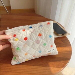 Detail of colorful polka dot quilted cotton mini pouch on a wooden table surface