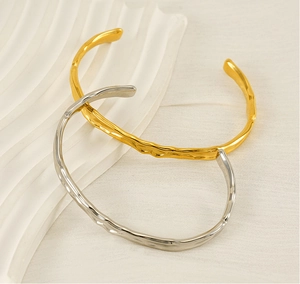 Dettaglio macro di bracciali a fascia martellati oro e argento con finitura lava