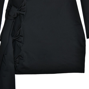 Détail d'une robe noire avec des nœuds latéraux, des volants et de longs rubans pendants