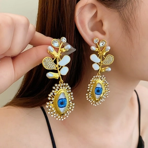 Close-up of vintage golden butterfly earrings with blue eye charms and rhinestones