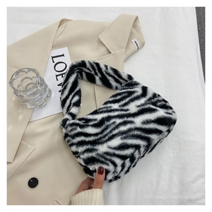 Top view of plush zebra print handbag on beige blazer with aesthetic props