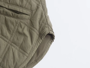 Detailed macro view of army green quilted cotton jacket showing pockets and hemline