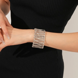 Gros plan détaillé d'un bracelet manchette en fils d'argent superposés sur un poignet