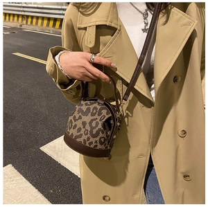 Street style view of a brown leather leopard bucket bag paired with a classic khaki trench coat
