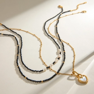 Layered gold necklace with heart shell pendant, black beads and white pearls