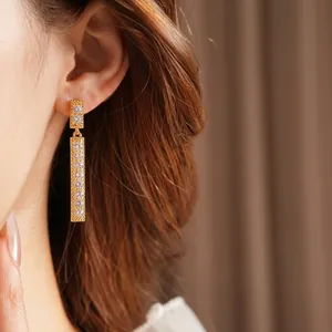 Luxury gold rectangular drop earrings with shimmering cubic zirconia stones on model