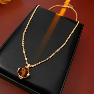 Makroaufnahme von Tigerauge-Anhänger mit goldener Kordelkette auf schwarzem Display