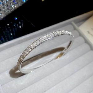 Macro detail of silver-colored pavé diamond bangle showing sparkling stones in a velvet box