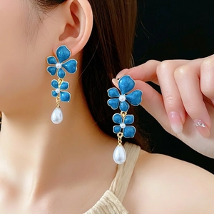 Vintage blue enamel flower earrings with pearls and gold base on a model