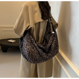 Leopard print crescent shoulder bag shown on model wearing a beige trench coat