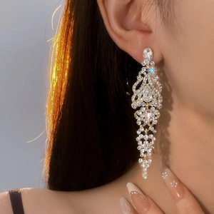 Elegant gold chandelier tassel earrings with crystals worn by model in warm lighting