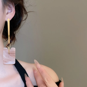 Close-up of pink marble pattern square pendant earrings with golden metallic accents