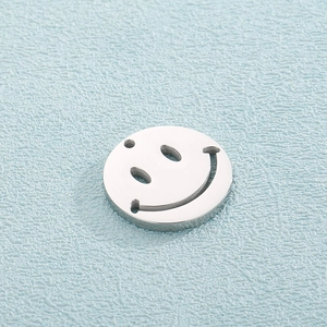 Detailed macro view of a silver stainless steel round pendant with a cutout smiley face design