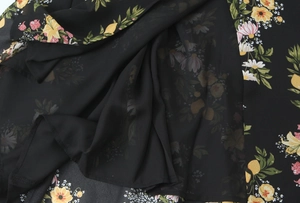 Detailansicht des Blumendrucks auf einem schwarzen Sommerkleid mit leichtem Futter