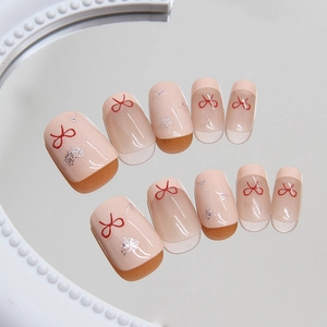 Unghie finte French rosa con fiocchi rossi e glitter argento su base a specchio
