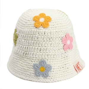 Close-up of handmade crochet texture and colorful floral patches on a white knit bucket hat