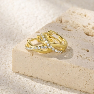 Macro detail of gold-finished S925 sterling silver twist hoop earrings with white zircon
