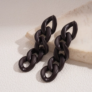 Detailed view of dark brown acrylic chain hoop earrings on a light stone slab pedestal