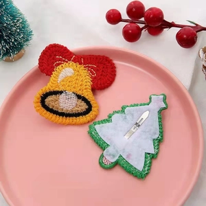Lot de barrettes de Noël tricotées avec cloche et sapin sur une assiette rose