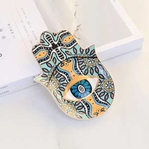 Detailed view of colorful ceramic Hamsa hand jewelry dish with Evil Eye pattern and gold rim
