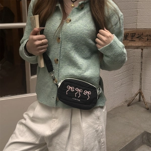 Detail of black quilted crossbody bag featuring pink bow embroidery and adjustable strap