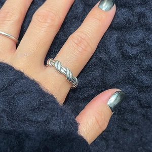 Detailed view of an irregular twisted rope silver ring worn on a finger