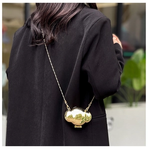 Close-up of a mini gold cloud-shaped shell bag with metallic finish and chain strap