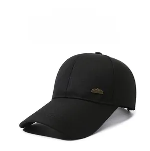 Detail of a black baseball cap featuring a mountain peak metal emblem on twill fabric