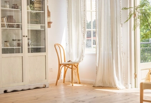 Close-up of white semi-sheer curtain featuring delicate pom-pom fringe and woven stripes
