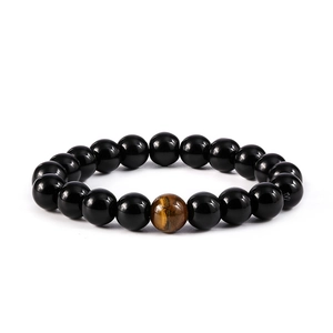 Detalle macro de pulsera elástica de cuentas con piedras negras y cuenta de ojo de tigre