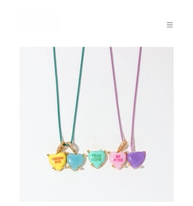 Detail of colorful enamel heart pendants with inspirational text and gold diamond-set clasps