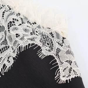 Detailed macro view of black fabric with white floral eyelash lace trim and embroidery
