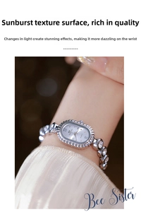 Detail of silver oval watch featuring a sunray dial and crystal-encrusted chain bracelet
