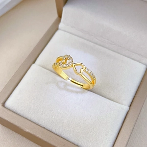Detail of gold-plated double heart ring with zircon inlay on a soft beige velvet box