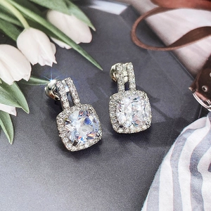 Close-up of square halo stud earrings with a clear zircon center and silver finish